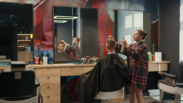 Barbershop: a woman barber cuts a client's man's hair