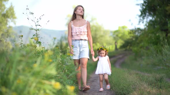 Happy Mother and Daughter with the Flower Wreath Walk in the Countryside