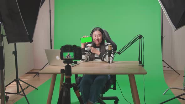 Camera Recording A Asian Woman Reviewing Green Screen Mobile Phone In Front Of Green Screen