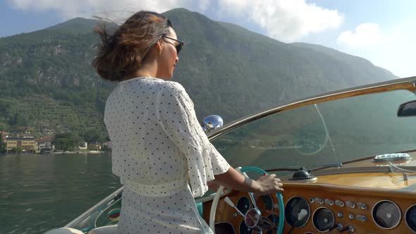 A woman on a classic luxury wooden runabout boat on an Italian lake