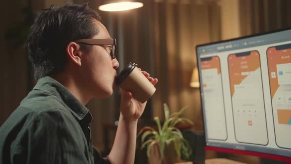 Asian Male Mobile Application Developer Works And Drinking Coffee With Graphics On Computer