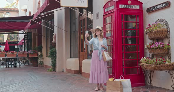 Cheerful Smiling Woman Is Having Fun and Making Selfie at Red Telephone Booth