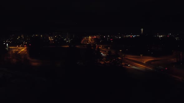 Night aerial flight over divided highway traffic through winter city