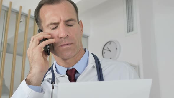 Doctor Talking on Phone with Patient Discussing Medical Report