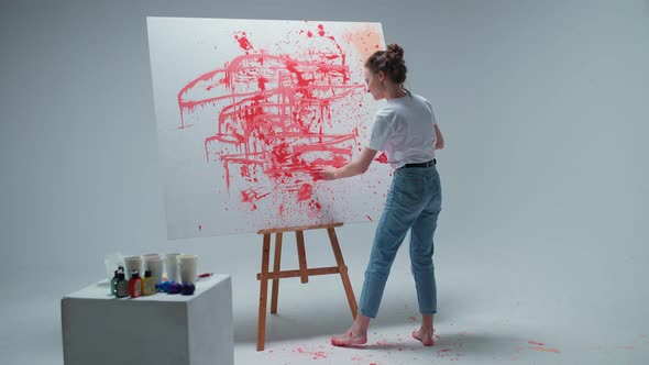 Young Woman Artist Draws with Her Hands on a Large Canvas in a White Room a Talented Artist Draws a