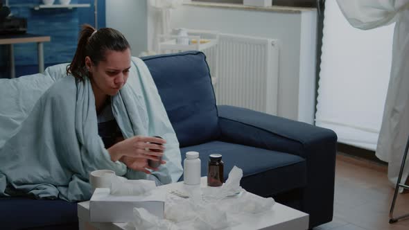 Sick Woman Looking at Bottle of Pills and Tablets with Capsules