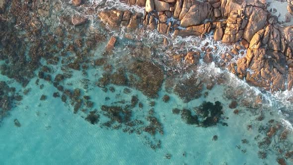 Aerial drone topdown moving away from  the ocean with crystal clear calm turquoise water in castle r