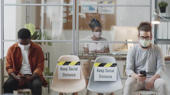 Multiethnic Office Workers in Masks Keeping Social Distance during Workday