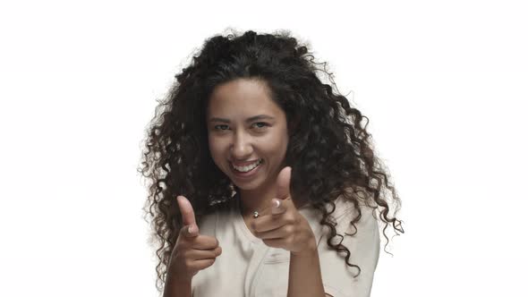 Closeup of Attractive Cheeky Woman with Dark Curly Hair Pointing Fingers at Camera and Smiling Need