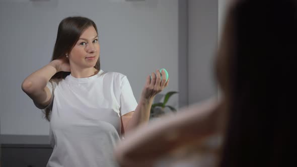 Young Woman Brushes Her Hair with a Comb