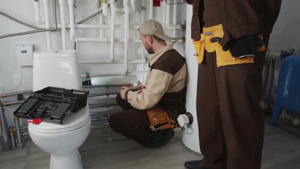 Plumbers Inspecting Pipes in Bathroom