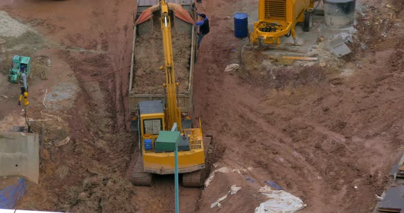 In Kuala Lumpur, Malaysia in the Pit Excavator Pours Earth Into a Truck