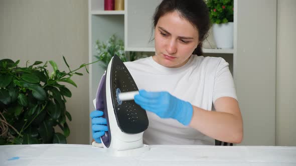 A Woman Cleans the Surface of the Iron with a Cleaning Pencil