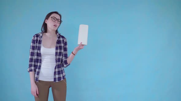 Frustrated Young Woman Standing on Blue Background and Holding Paper Towels