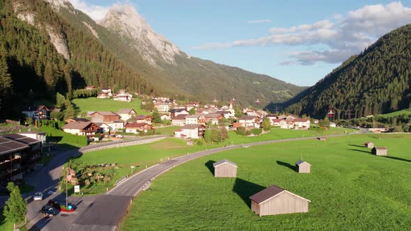 Aerial View of an Austrian Village in a Green Mountain Valley at Sunset Alps