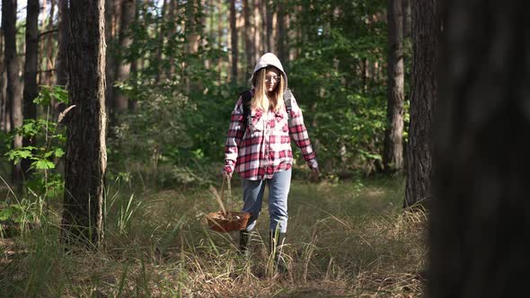 Young Confident Woman Searching Mushrooms in Forest with Tree Passing at Front