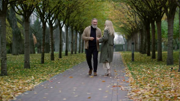 Wide Shot of Smiling Happy Couple Having Fun in Beautiful Foliage Park