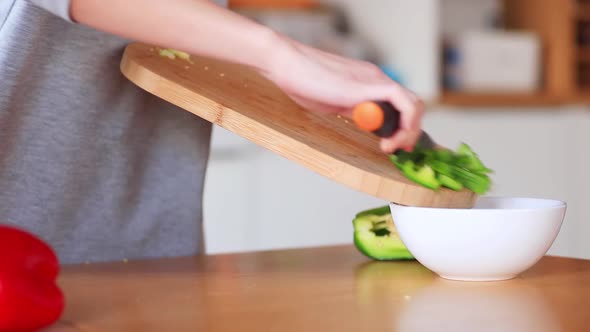 woman cutting vegetables with knife on kitchen table