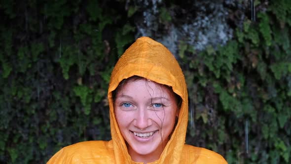 Portrait of a Blue-eyed Woman in a Yellow Rain Coat Looks and Smiles Into the Camera