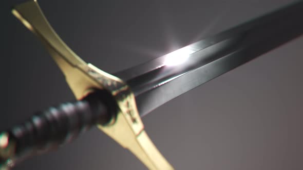 Old medieval sword shining in a spotlight. Light reflects in a sharp blade. 4KHD