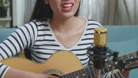 Close Up Of A Woman With Microphone Singing And Playing Guitar At Home