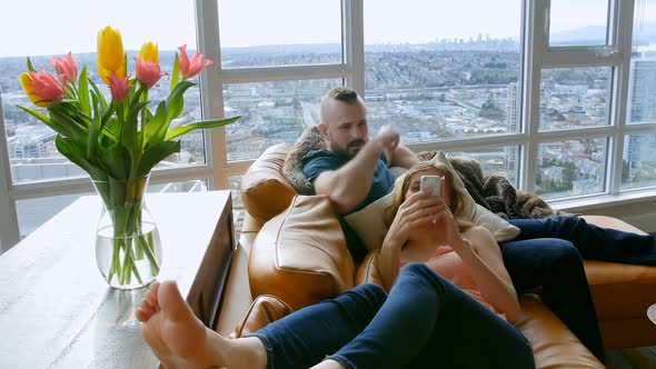 Couple using digital tablet and mobile phone in living room 4k