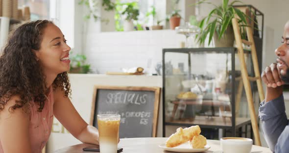 Happy diverse couple spending time together at cafe, drinking coffee and talking