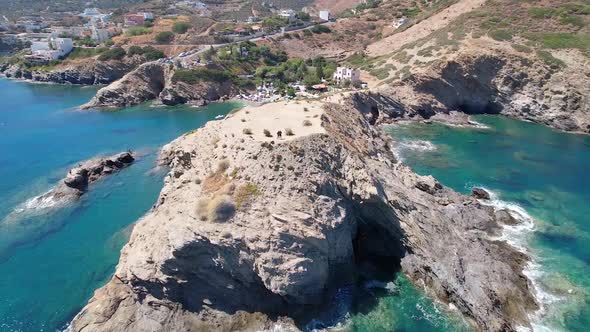 Drone flies over the rocky nature and blue sea with swimmers and boat in sight