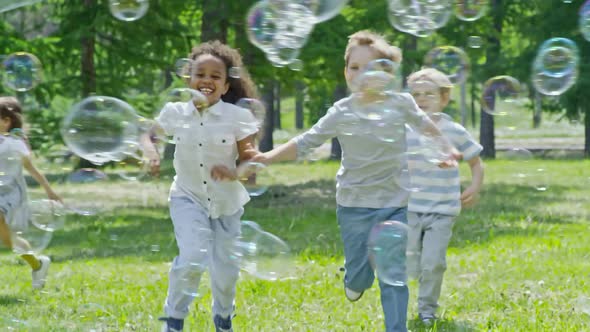 Funny Kids Running and Playing with Bubbles at Sunny Day alt