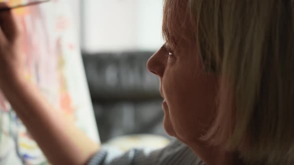 Close up video of senior woman painting while sitting at home. Shot with RED helium camera in 8K.