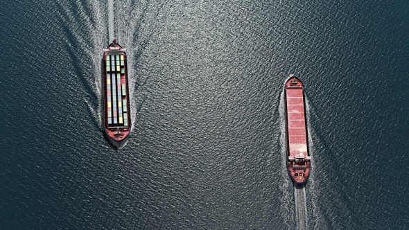 Two cargo ships sailing close, one to dock and one to leave Harbor