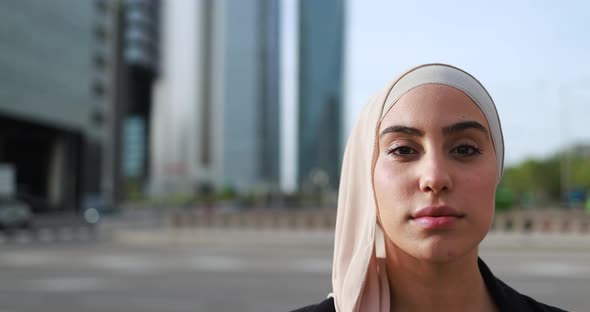 Muslim business woman looking on camera outdoor with city in background