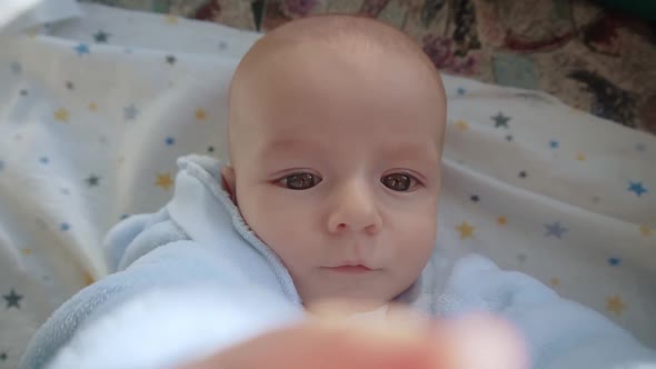 Funny Baby Lies in Bed and Looks Into the Camera