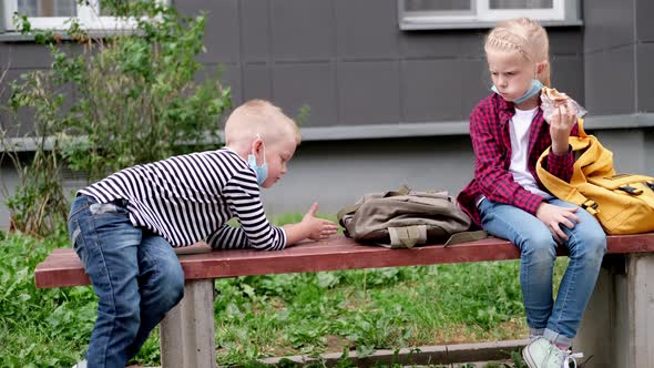 Back to School Girl and Boy Children Sit Talking on Bench Near the School Keeping Social Distance