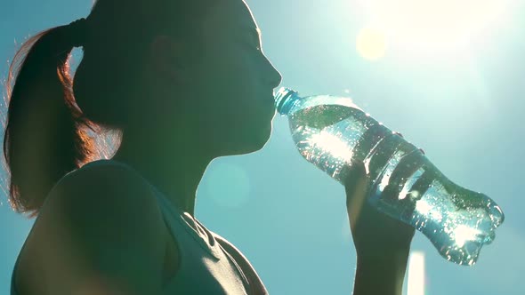 Sporty Woman Drinking Water Outdoor on Sunny Day