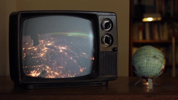 Earth from Space Seen on a Retro TV near a Globe Map. Zoom In.