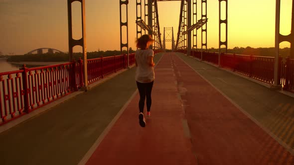 Woman Is Running Along the Bridge