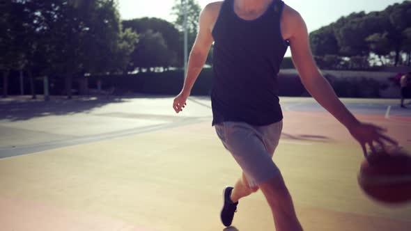 Basketball Player Trains Himself on a Basketball Court with a Ball