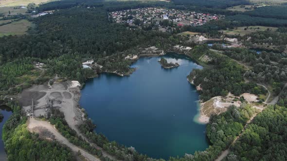 Aerial View of lake with Beautiful Water in a Quarry Surrounded by Forest, Small Town and Mining Ope