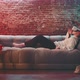 Young woman laying on couch wearing vr goggles - VideoHive Item for Sale