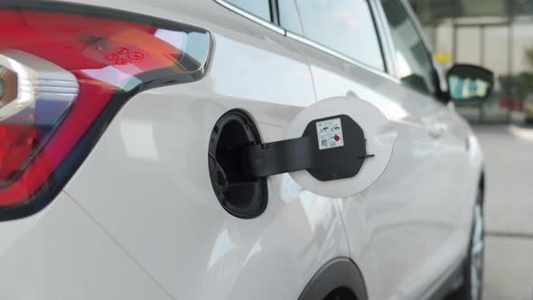 Woman Inserts a Fuel Gun in a Gas Tank To Refuel a Car