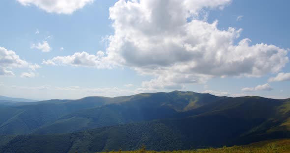 High Mountains Are Covered With Forests. Clouds Float Over The Mountains