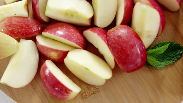 Slices of red apples and knife on chopping board