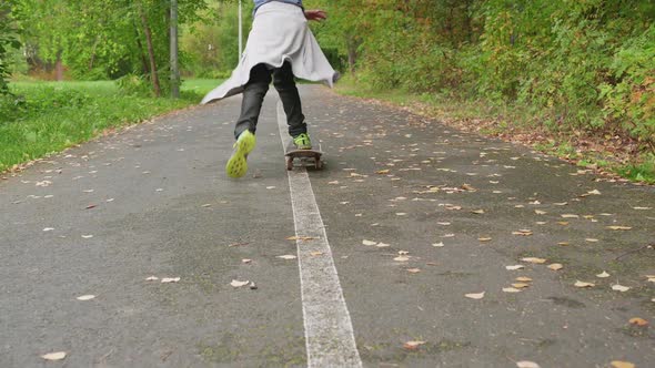 Teenager Boy Skateboarding on City Park Rear View