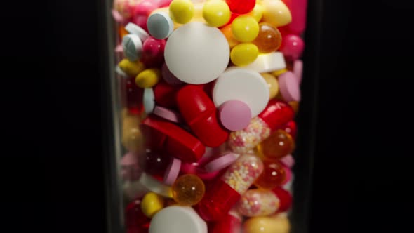 Closeup of Coloured Medicine Tablets in Glass Rotation on Black Background Shooting of Red and