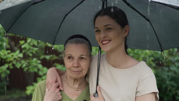 Old and Young Women Under Umbrella in the Rain