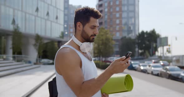 Side View of Indian Man Using Smartphone App After Training Outdoors