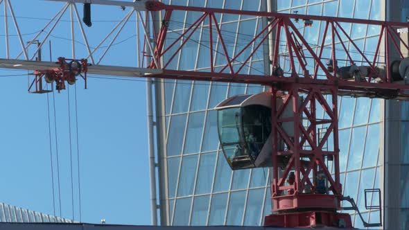 construction crane is working on a construction site against the background of a glass modern buildi