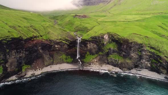 Aerial view of small waterfall ending on North Atlantic sea, Faroe island.