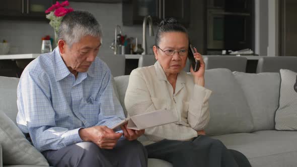 Front view of old senior asian couple using multimedia device in a comfortable home 4k